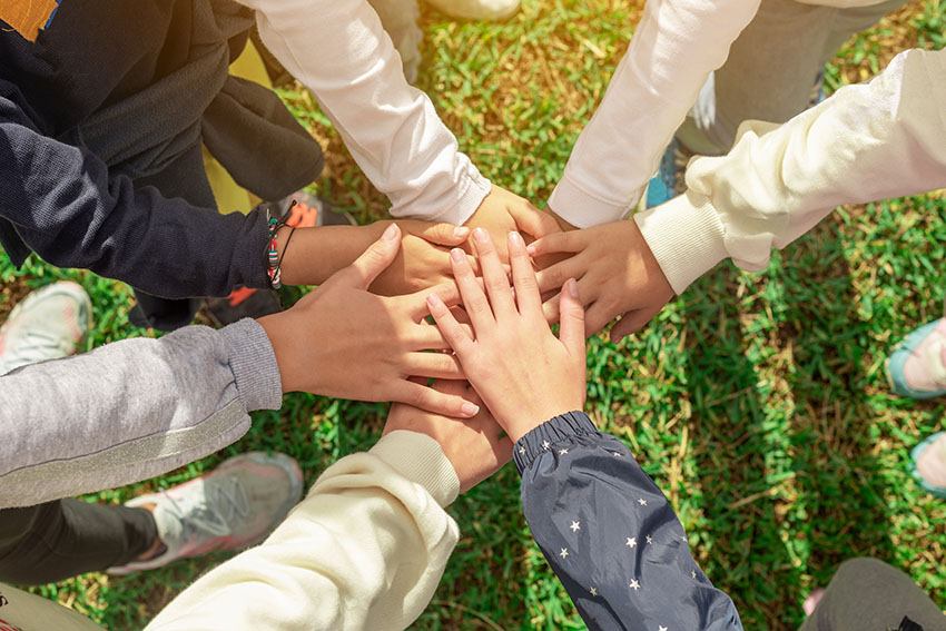 A group of children’s hands joined at the center. Cooperation an